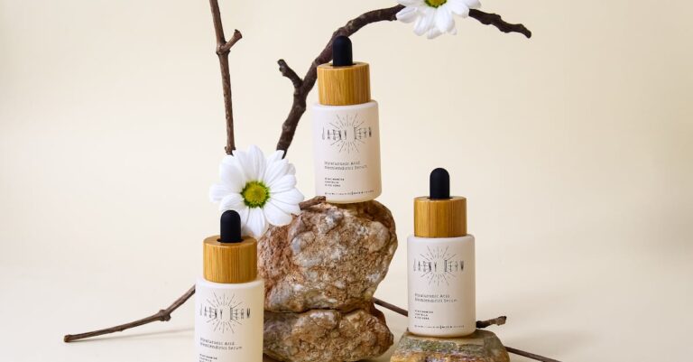 Organic hyaluronic acid serum bottles with floral and stone arrangement on neutral background.